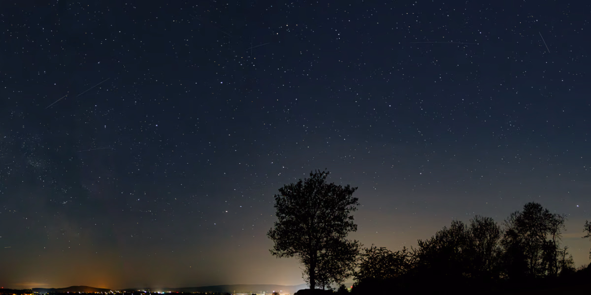 Nachthimmel am Benther Berg, 26.4. 4:00 Uhr, Am Hapkenberge, Baum im Vordergrund, die Lichter von Gehrden im Hintergrund. Am Himmel der Stern Antares, ein Hauch Milchstrasse